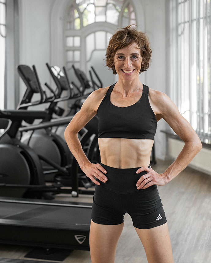 Inhaberin des SwissFit Fitnessstudios steht im Wintergarten vor den Cardiogeräten.